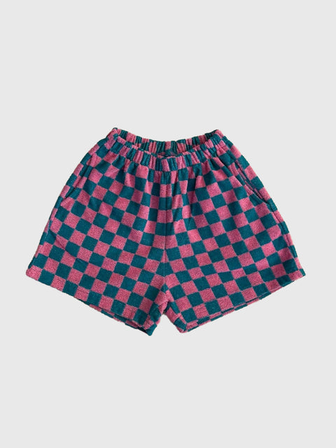 Checkered shorts with pink and green pattern on a light gray background