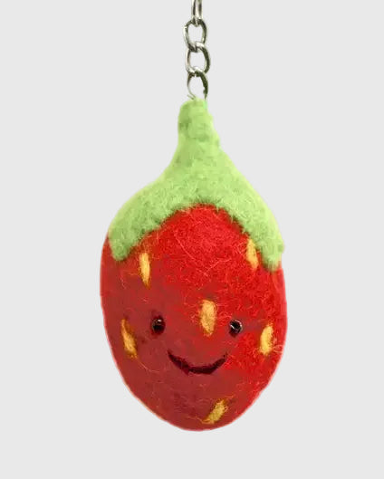 A cute, hand-felted strawberry keychain with a smiling face, featuring a red body with yellow seeds, a green felt top, and a silver metal key ring on a plain white background.
